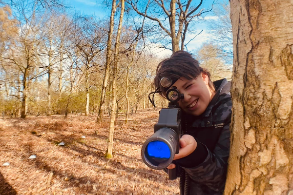Person playing laser tag standing next to a tree