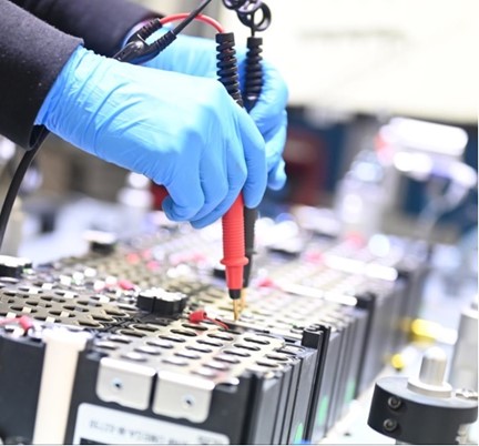 Hands wearing blue gloves making batteries