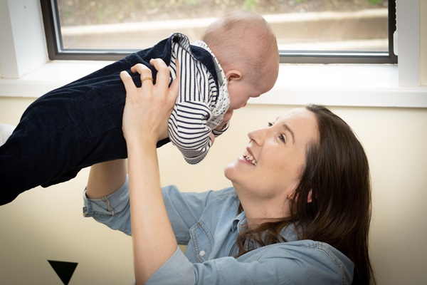 Mother holding a baby above her head and looking at its face smiling